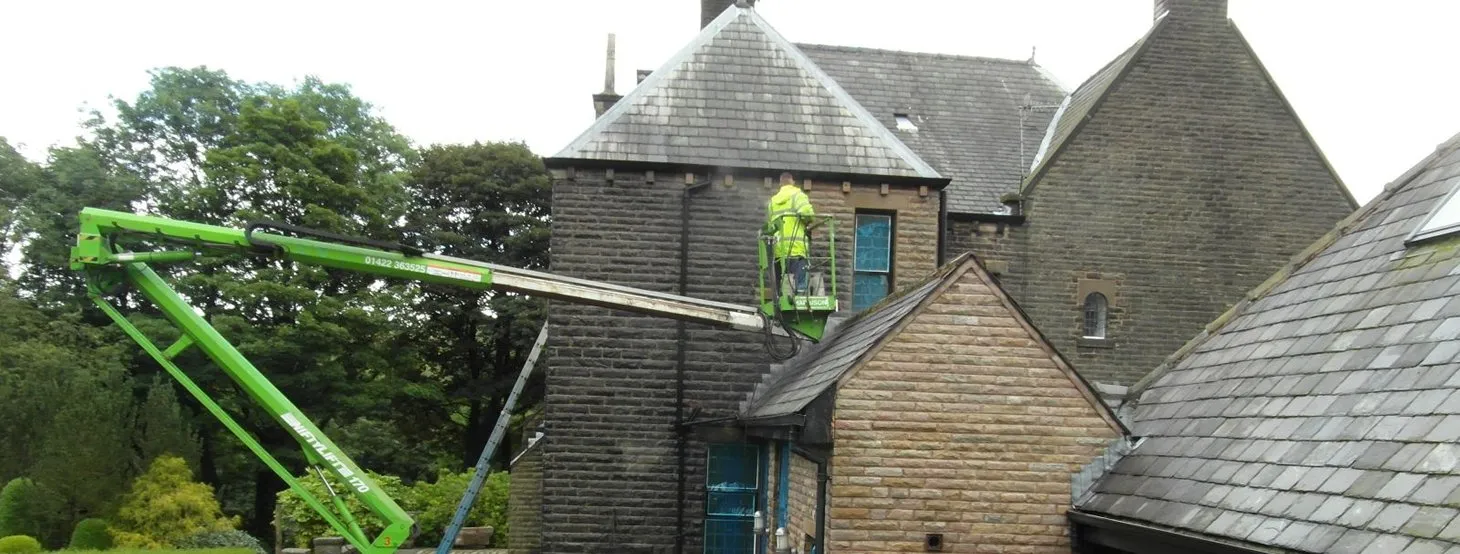 Cleanwalls sandblasting a large stone property from an access platform